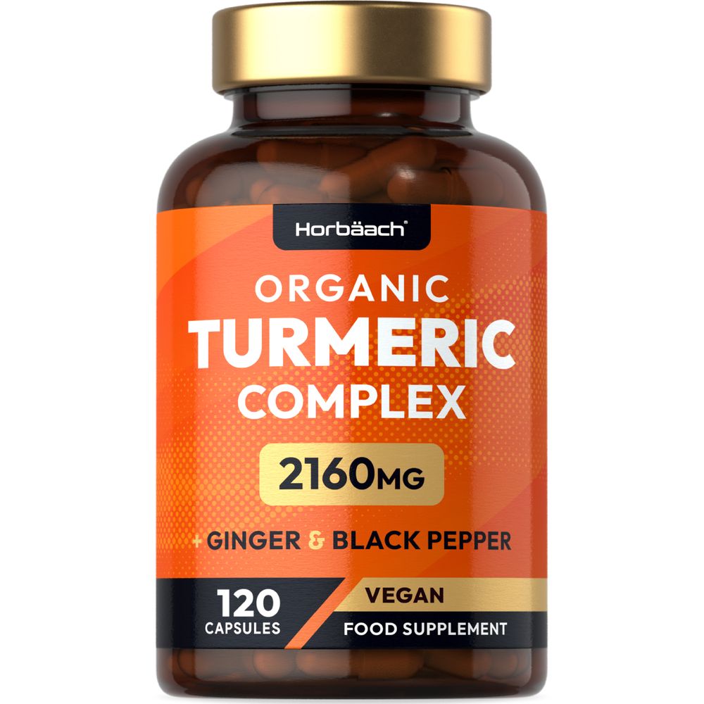 Hand holding bottle of Brown Organic Turmeric Complex, containing 120 vegan capsules for health benefits and wellness support.