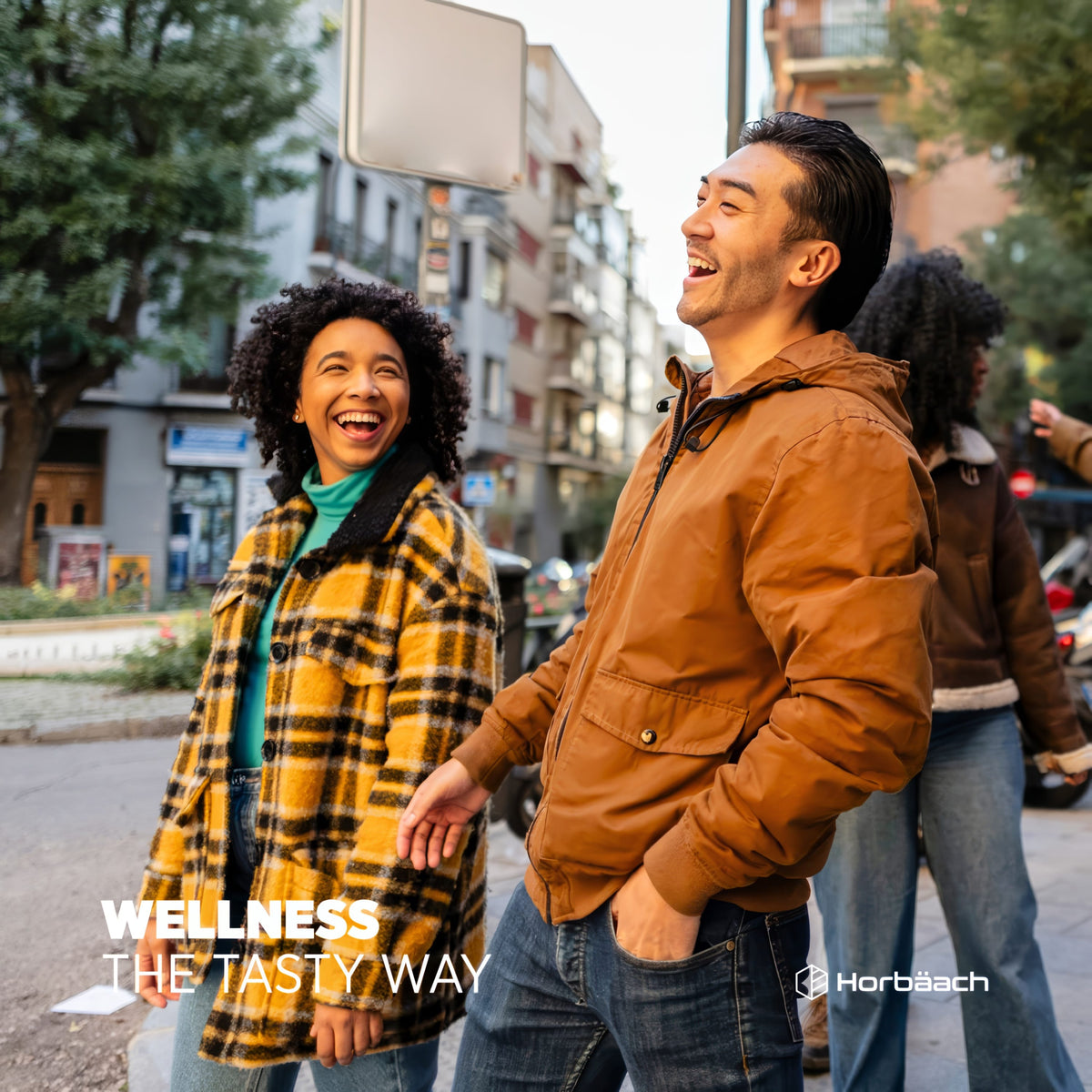 Two young adults joyfully laugh and walk on a city street, promoting Biotin Gummies.