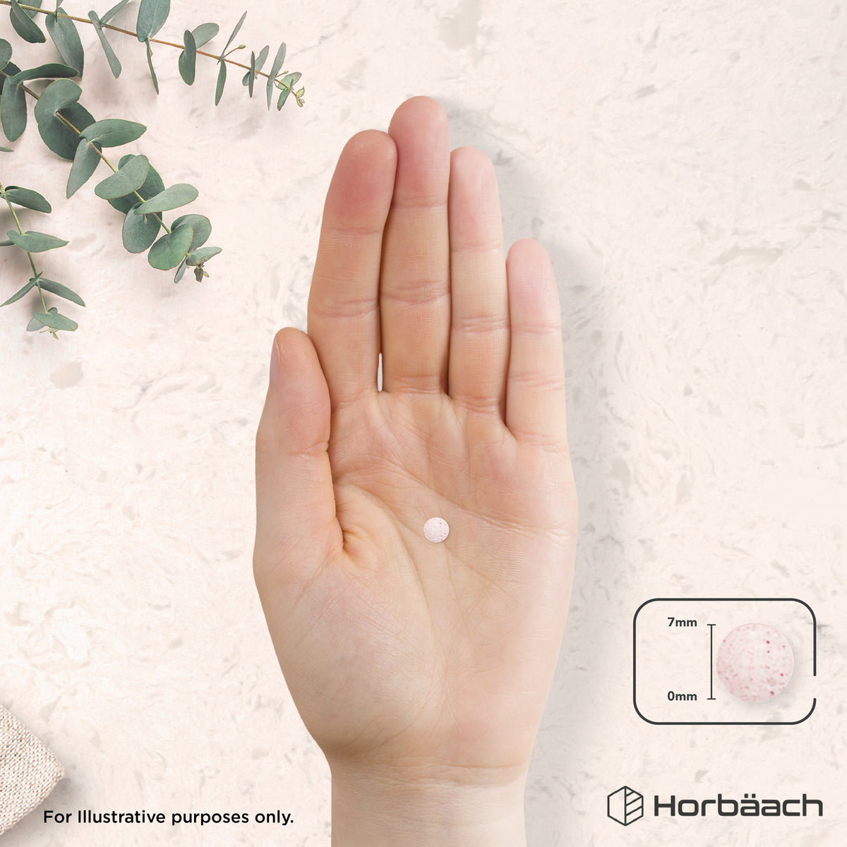 A small, round, light pink tablet with red speckles, 7mm in diameter and 0mm thick, held in a hand.
