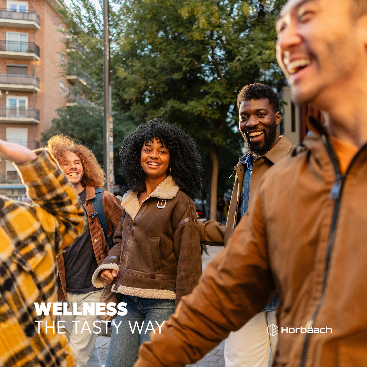 A diverse group of young adults enjoys a walk and laughter on a city street.