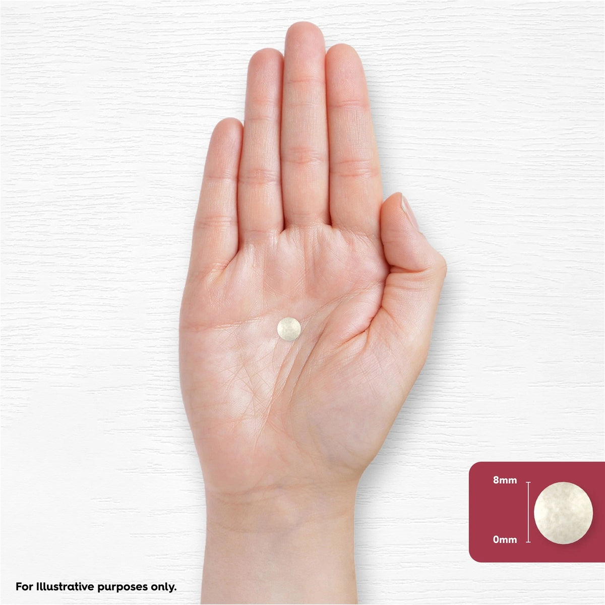 A single 8mm round tablet in an open hand, highlighting size and form.