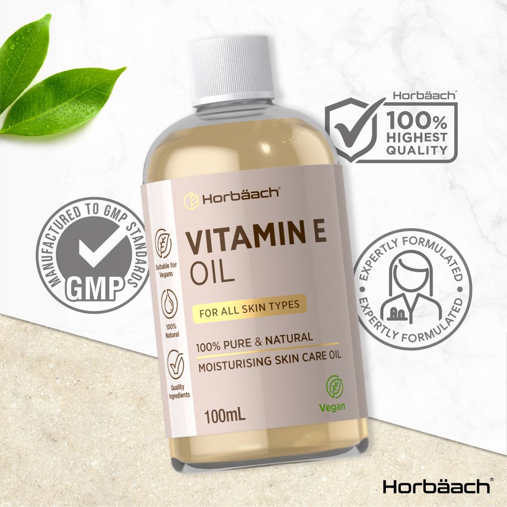 Hand holding a scale with Vitamin E Oil 100mL liquid bottle, emphasizing product size and volume.