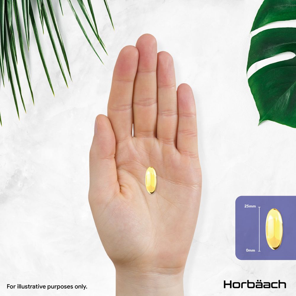 A 25mm long yellow softgel is displayed on a hand scale.