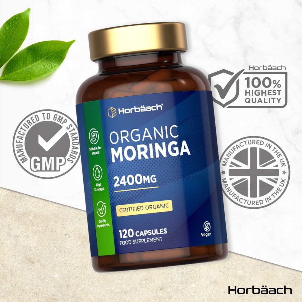 Hand holding a scale with a bottle of organic Moringa 2400mg, containing 120 vegan capsules.