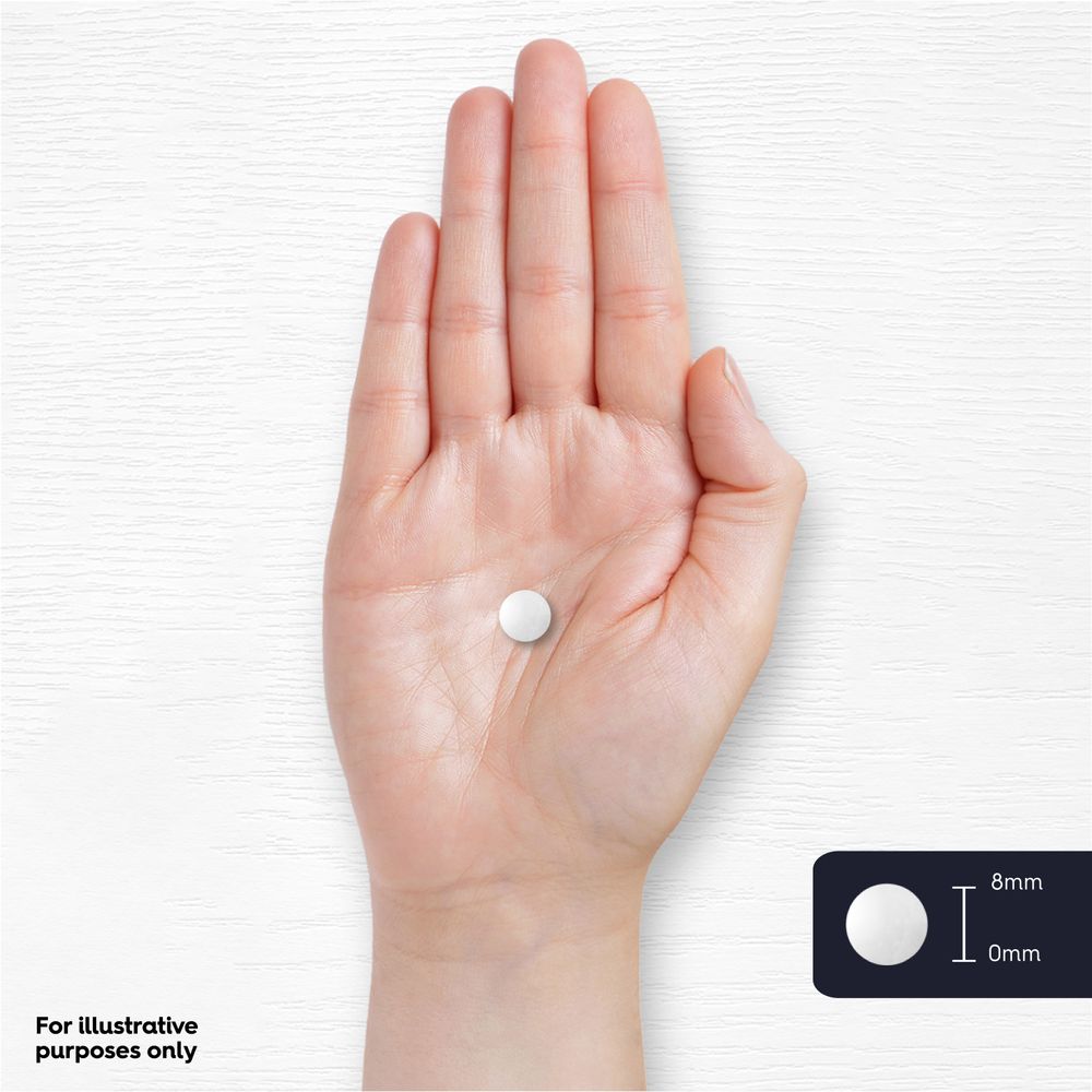 A small 8mm white round tablet sits on the palm of a hand.