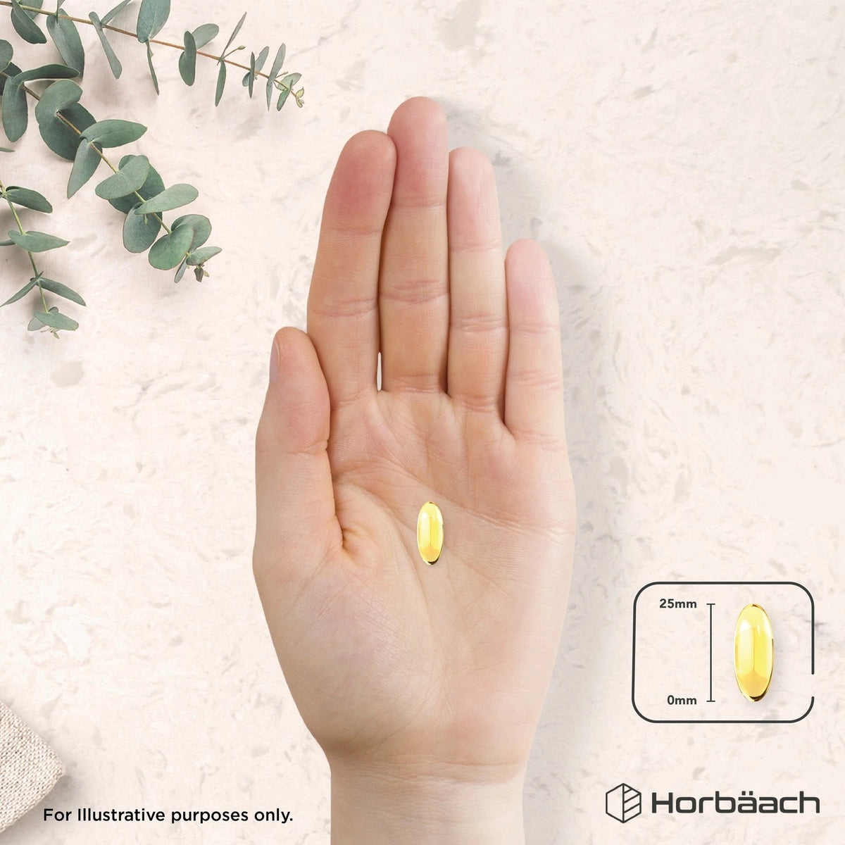 A 25mm long yellow oval softgel capsule is resting on a hand.