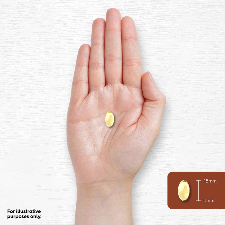 A 15mm yellow softgel capsule rests on the palm of a hand.